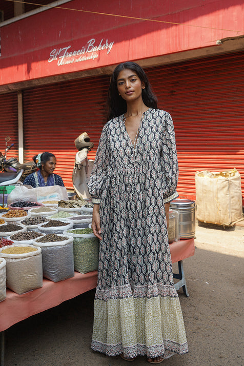 Bhoomi Maxi Dress Onyx — full length front view at Indian spice market, onyx hand block print maxi dress with V-neckline and tiered hem, colourful spice stall India | Daughters of India