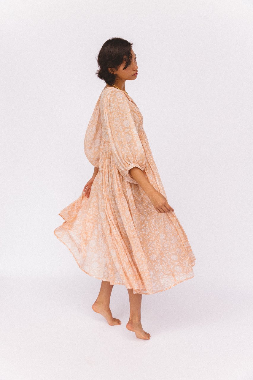 Daughters of India Kyra Midi Dress in Apricot Blush — studio side view twirling, flowing skirt and billowed sleeves