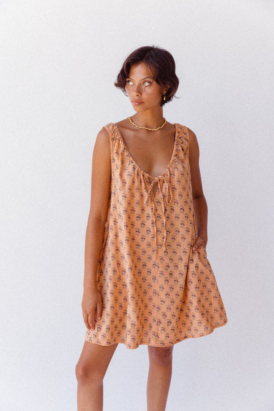 Sundress Mini Peach — outdoor scenic portrait, model in natural landscape, mini hemline showing, hand block print peach cotton dress, Jaipur artisan ethical Indian fashion | Daughters of India