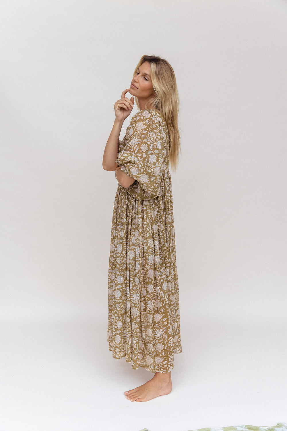 Daughters of India Kyra Maxi Dress in Olive — studio side profile, finger on chin, gathered waist detail